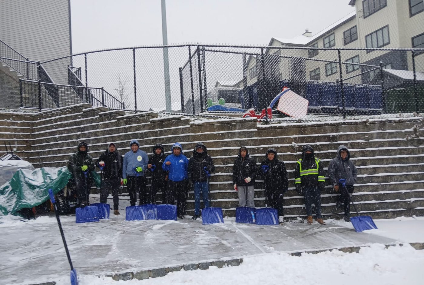 Shaleg Landscaping crew with snow shovels on a cleared lot in falling snow